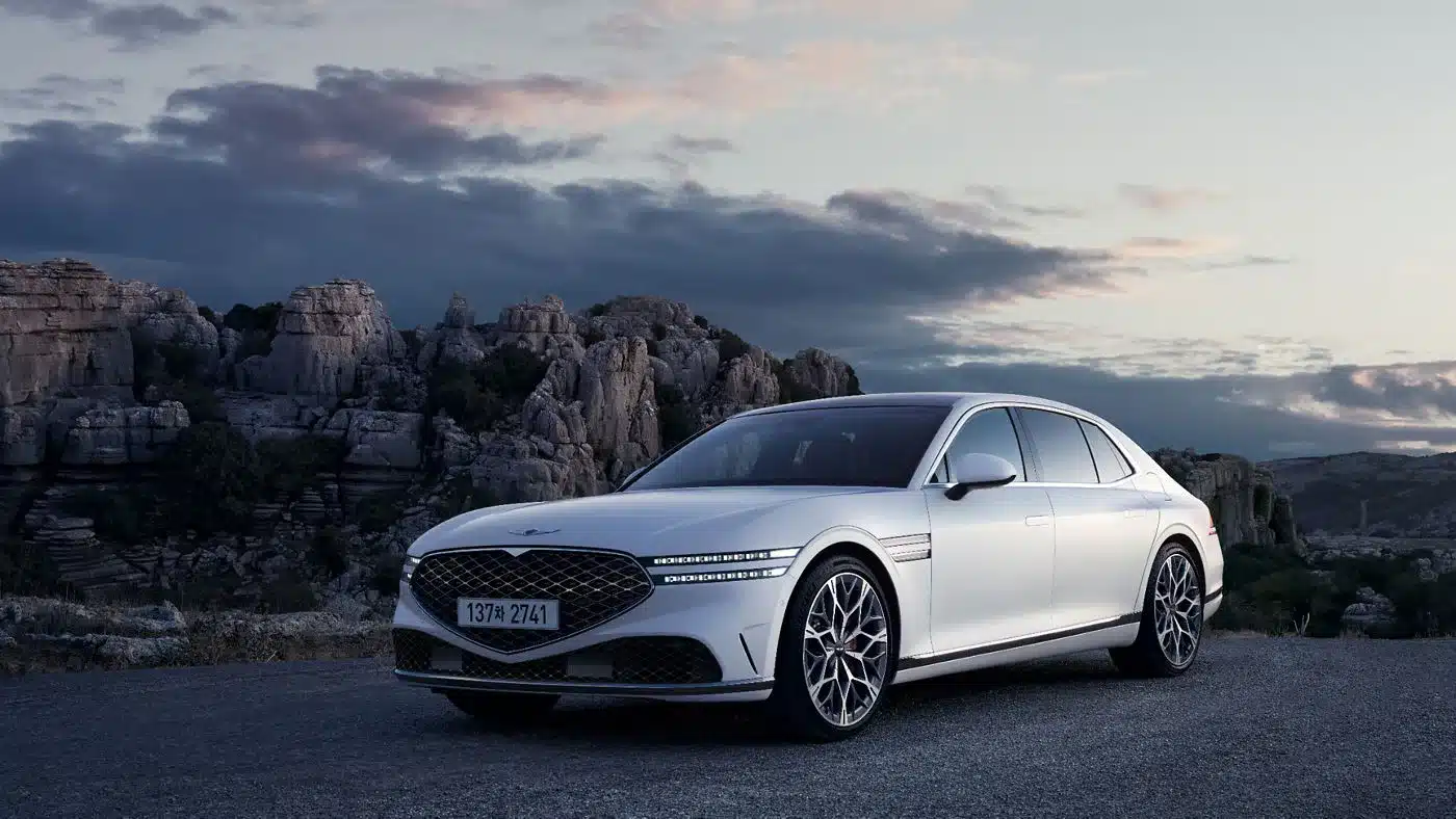 Genesis G90 Limousine in weiß, geparkt vor Felsenlandschaft bei Sonnenuntergang