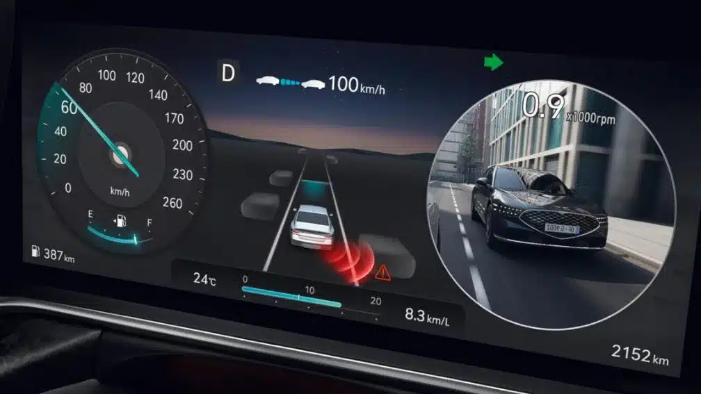 Digitales Kombiinstrument im Genesis G90 zeigt Fahrdaten und Seitenkamera-Ansicht.