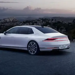 Weißer Genesis G90 von hinten auf einer Straße, umgeben von Bergen und bewölktem Himmel