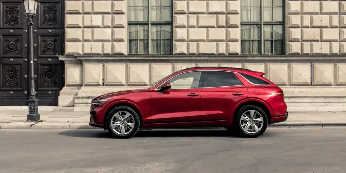 Genesis GV70 in Rot, seitlich vor einem historischen Gebäude geparkt