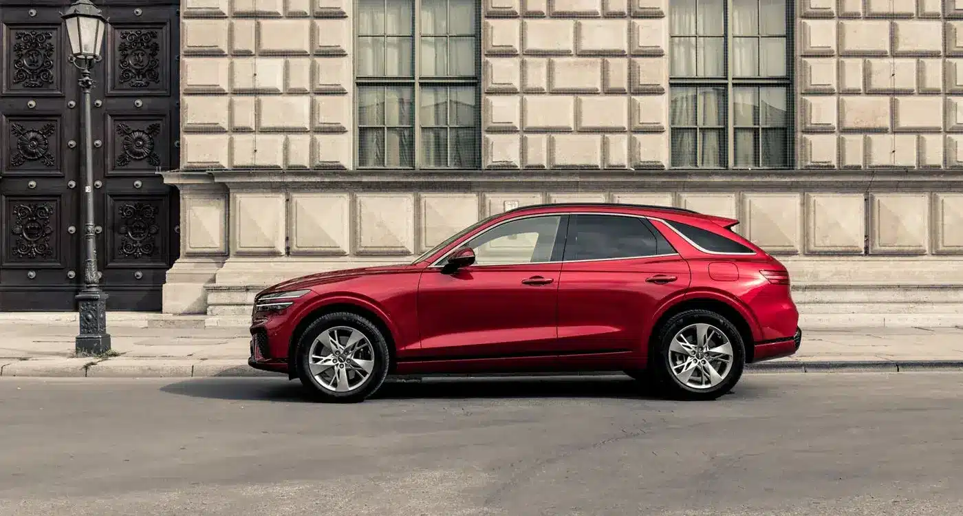 Genesis GV70 in Rot, seitlich vor einem historischen Gebäude geparkt