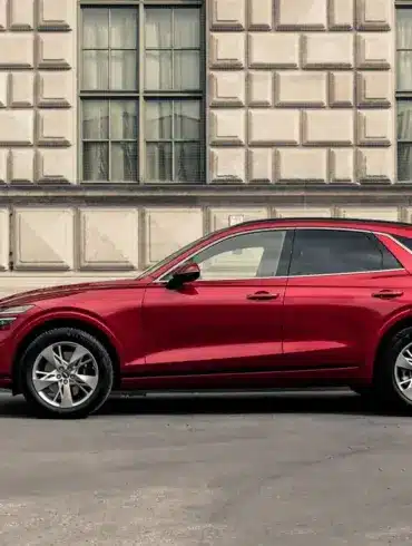 Genesis GV70 in Rot, seitlich vor einem historischen Gebäude geparkt