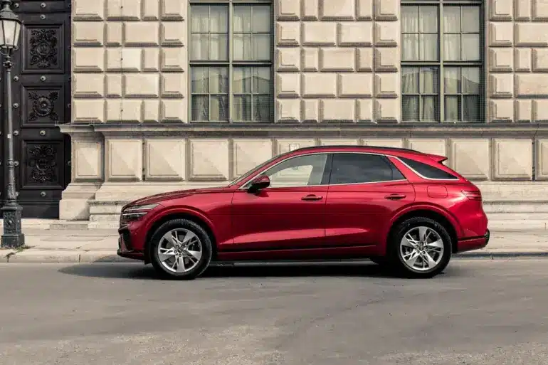 Genesis GV70 in Rot, seitlich vor einem historischen Gebäude geparkt