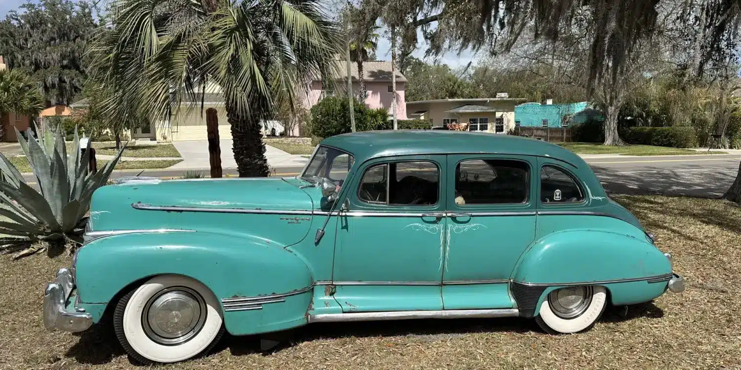 Historischer Hudson Super Six von 1947 in Türkis, Seitenansicht, mit Vier-Tür-Karosserie, weißen Reifen und Chromdetails.