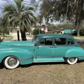 Historischer Hudson Super Six von 1947 in Türkis, Seitenansicht, mit Vier-Tür-Karosserie, weißen Reifen und Chromdetails.