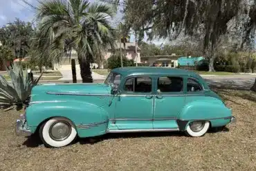 Historischer Hudson Super Six von 1947 in Türkis, Seitenansicht, mit Vier-Tür-Karosserie, weißen Reifen und Chromdetails.