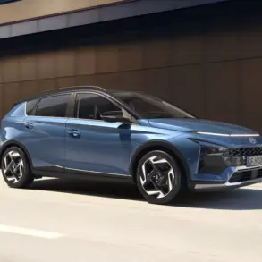 Blauer Hyundai BAYON fährt auf einer Straße entlang einer modernen Gebäudefassade