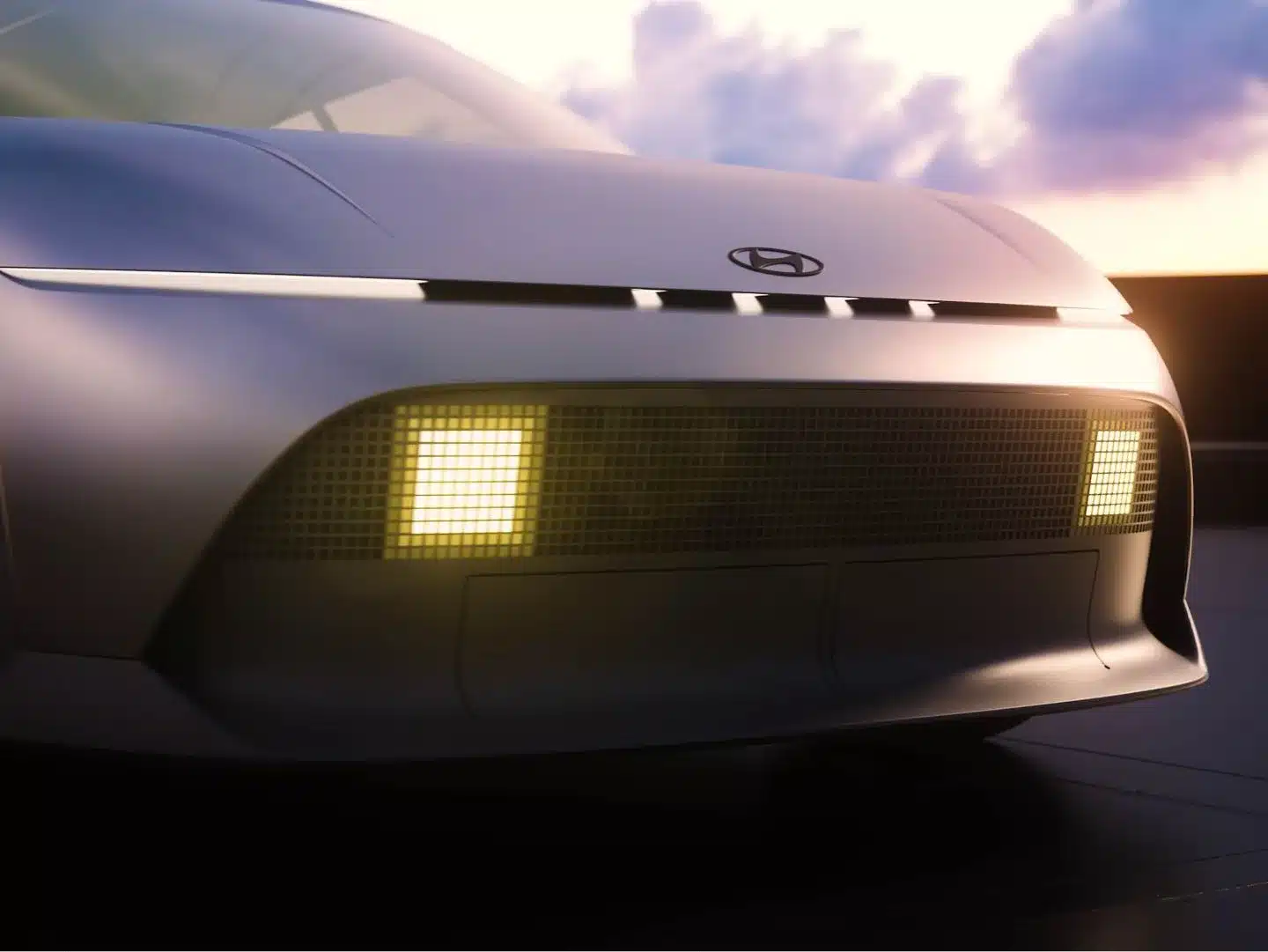 Frontpartie des Hyundai Concept THREE mit modernen Leuchten und klaren Linien, aufgenommen bei Sonnenuntergang.