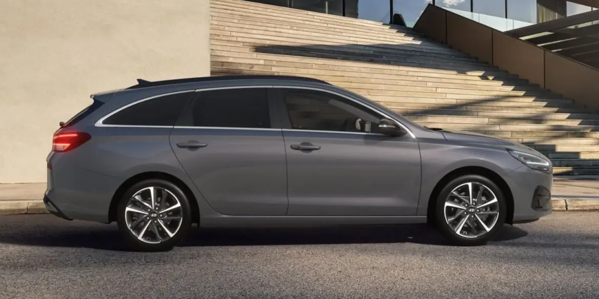 Seitenansicht des Hyundai i30 Kombi in Grau vor einem modernen Gebäude mit Treppe