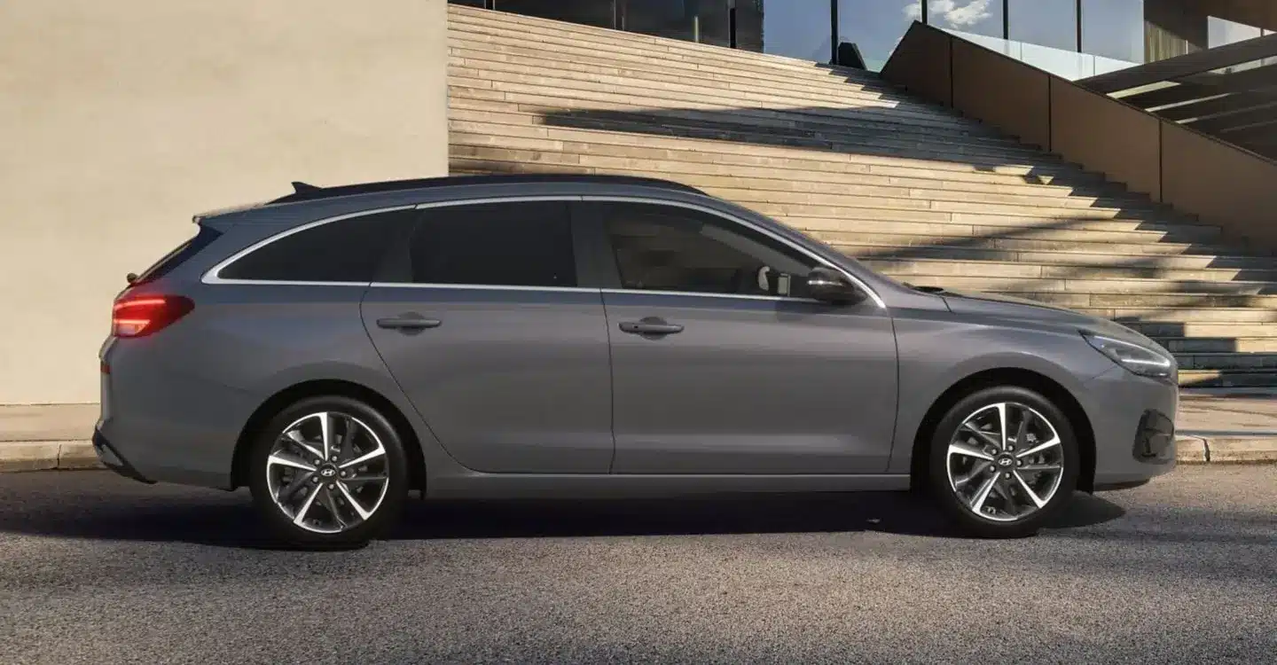 Seitenansicht des Hyundai i30 Kombi in Grau vor einem modernen Gebäude mit Treppe