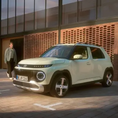 Hyundai INSTER Elektroauto steht vor einem modernen Gebäude auf einem Parkplatz.