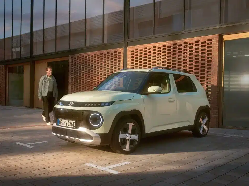 Hyundai INSTER Elektroauto steht vor einem modernen Gebäude auf einem Parkplatz.