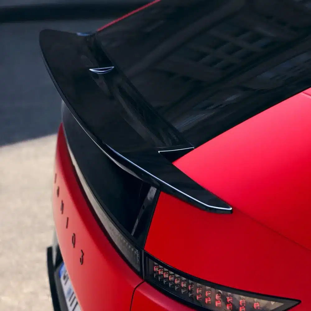 Heckansicht eines roten Hyundai IONIQ 3 mit markantem schwarzen Spoiler und LED-Rückleuchten.