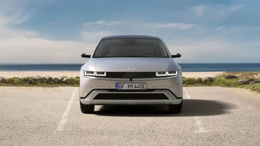 Hyundai IONIQ 5 silberfarben, frontal fotografiert auf einem Parkplatz vor Meer und Himmel