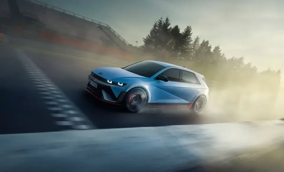 Hyundai IONIQ 5 N in blauer Lackierung driftet dynamisch über eine Rennstrecke bei Sonnenuntergang.
