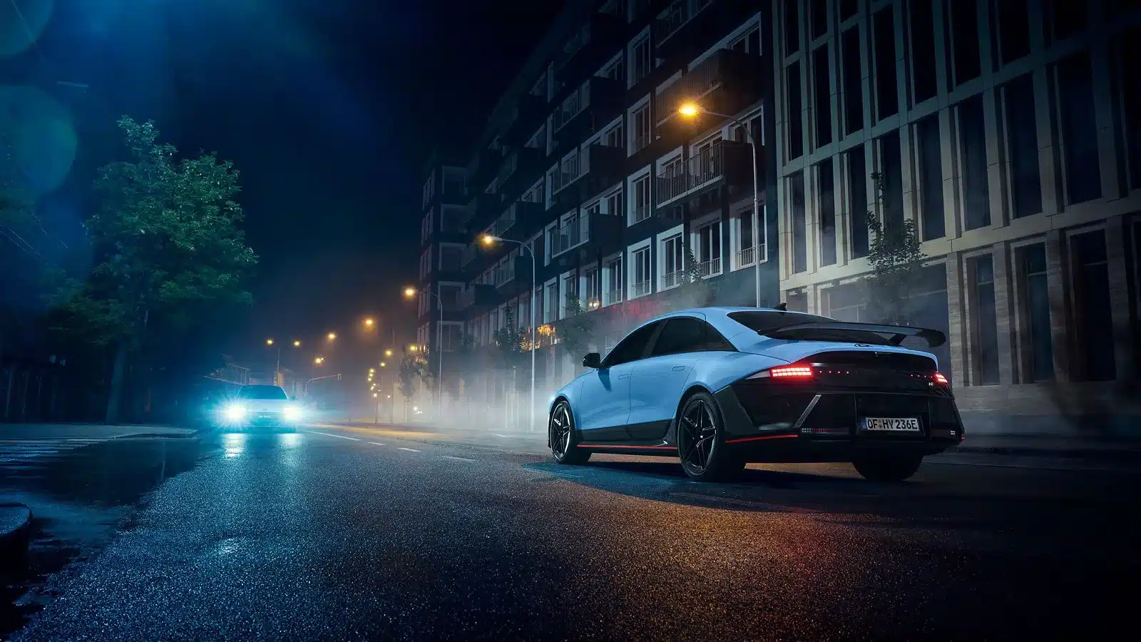 Hyundai IONIQ 6 N fährt bei Nacht durch eine beleuchtete Straßenkulisse