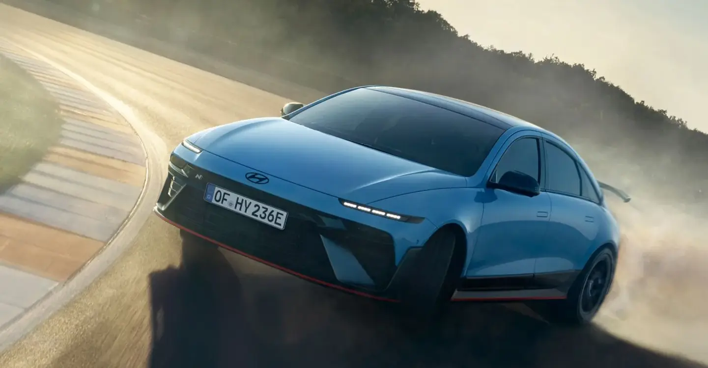 Hyundai IONIQ 6 N fährt dynamisch durch eine Kurve auf einer sonnigen Rennstrecke.