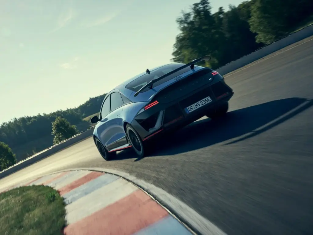 Hyundai IONIQ 6 N in Kurvenfahrt auf einer abgesperrten Rennstrecke, Heckansicht mit Spoiler