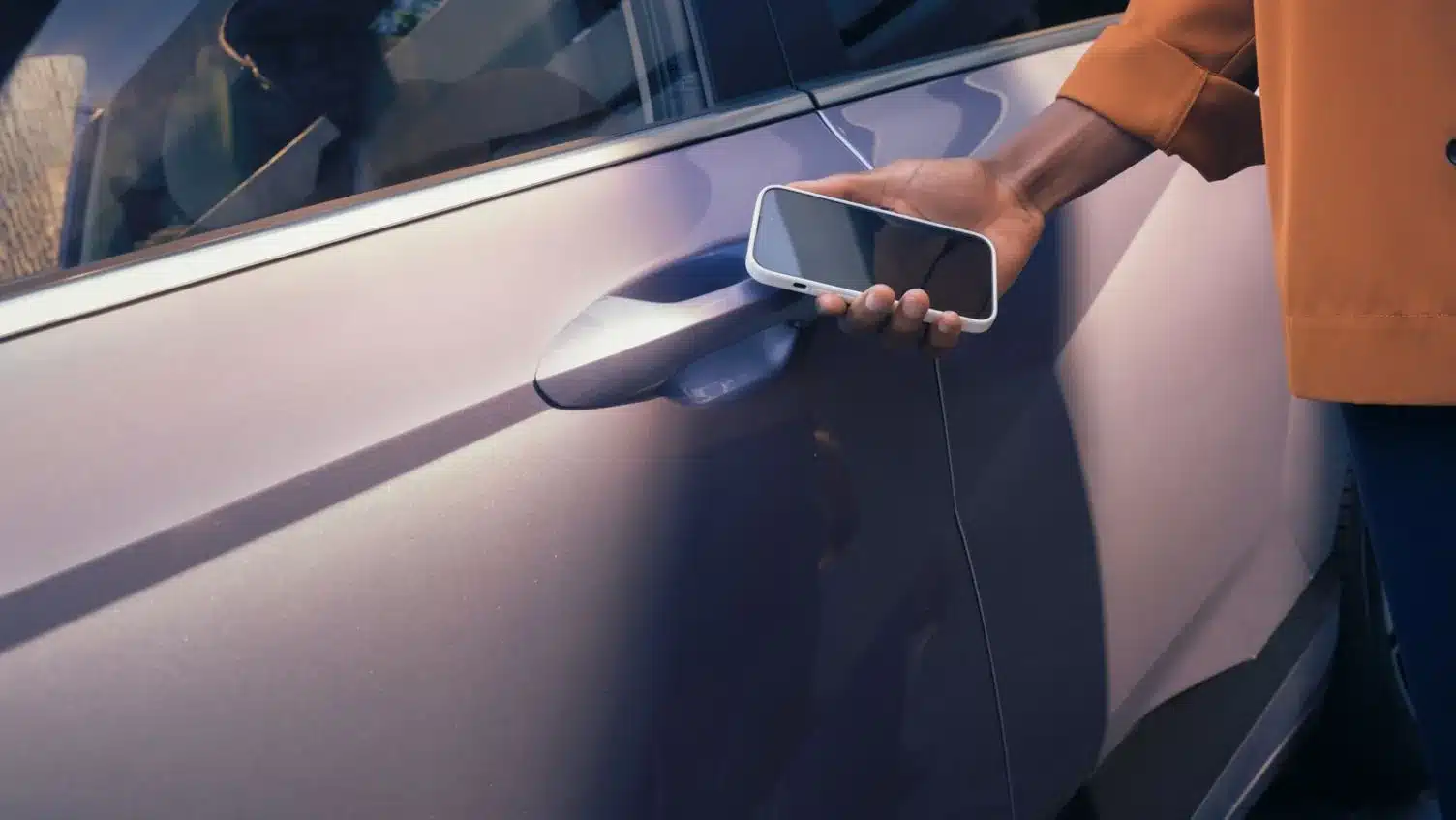 Hand hält Smartphone an den Türgriff eines Hyundai KONA Elektro zum digitalen Entriegeln.