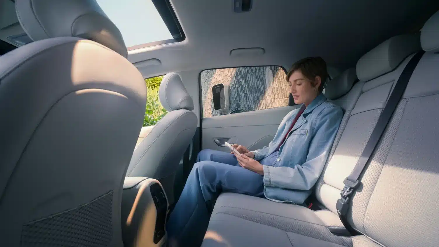 Person sitzt entspannt auf der Rückbank eines Hyundai KONA Elektro.