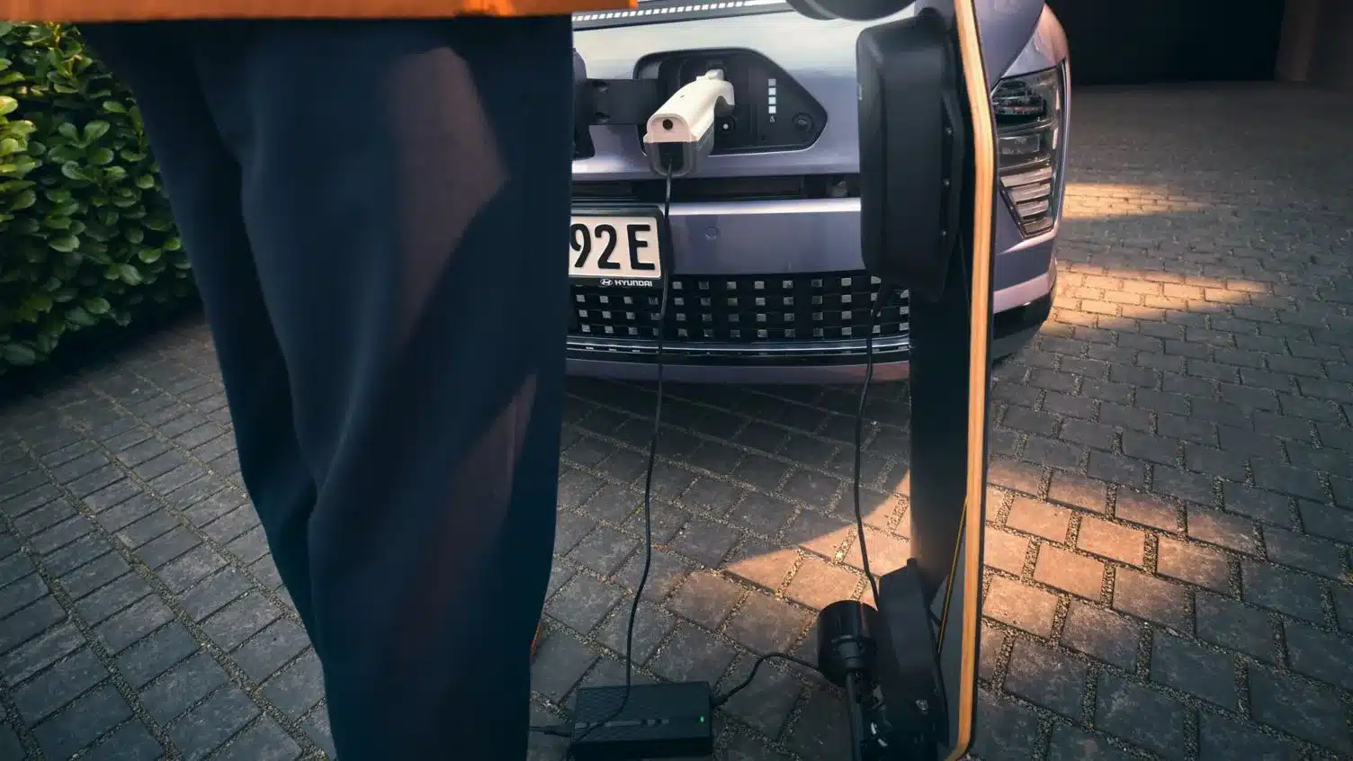 Hyundai KONA Elektro wird über den Ladeanschluss an der Front geladen. Ein externer Verbraucher ist angeschlossen.