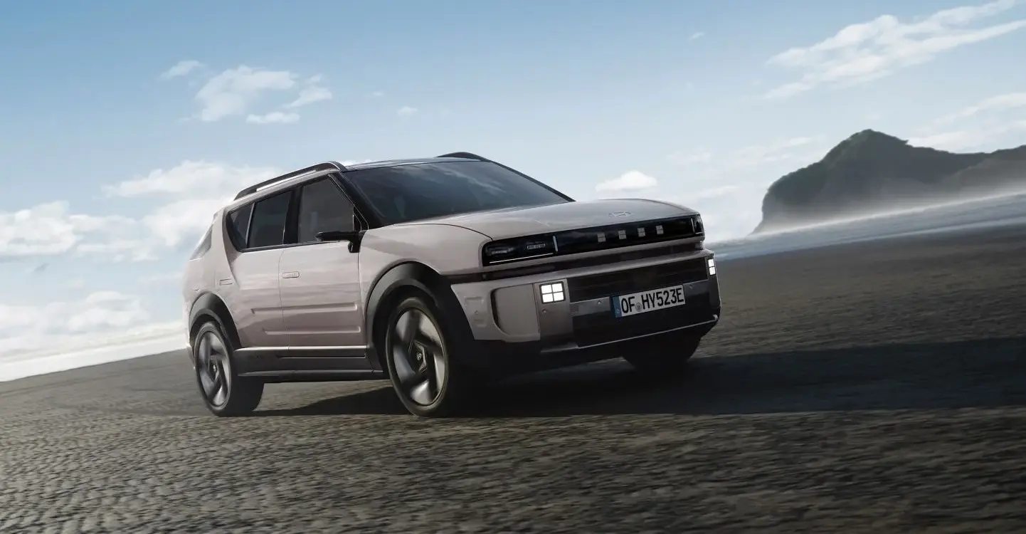 Futuristischer SUV auf offener Straße bei Tageslicht, im Hintergrund eine Berglandschaft