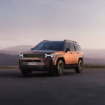 Hyundai Santa Fe Plug-in-Hybrid SUV in kupferfarbener Lackierung steht vor einer malerischen Berglandschaft bei Sonnenuntergang.