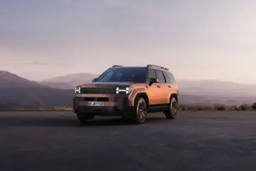 Hyundai Santa Fe Plug-in-Hybrid SUV in kupferfarbener Lackierung steht vor einer malerischen Berglandschaft bei Sonnenuntergang.