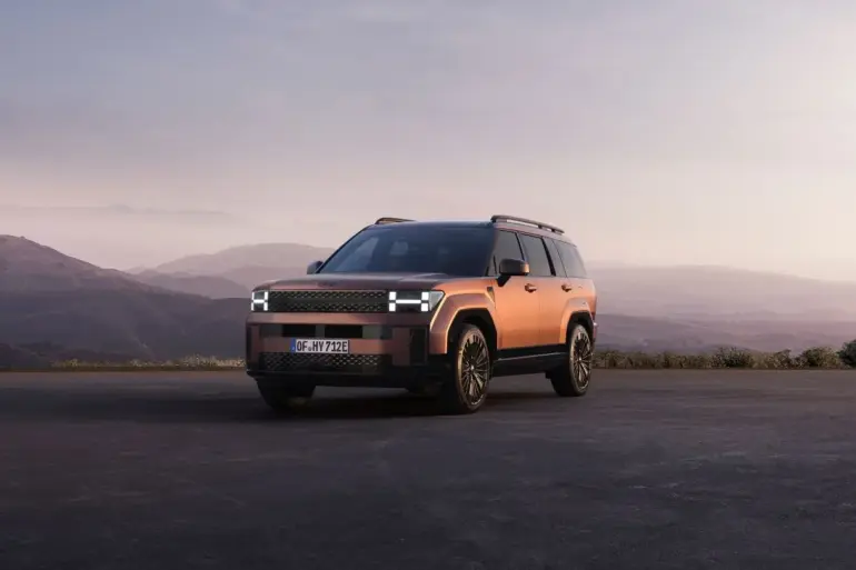Hyundai Santa Fe Plug-in-Hybrid SUV in kupferfarbener Lackierung steht vor einer malerischen Berglandschaft bei Sonnenuntergang.