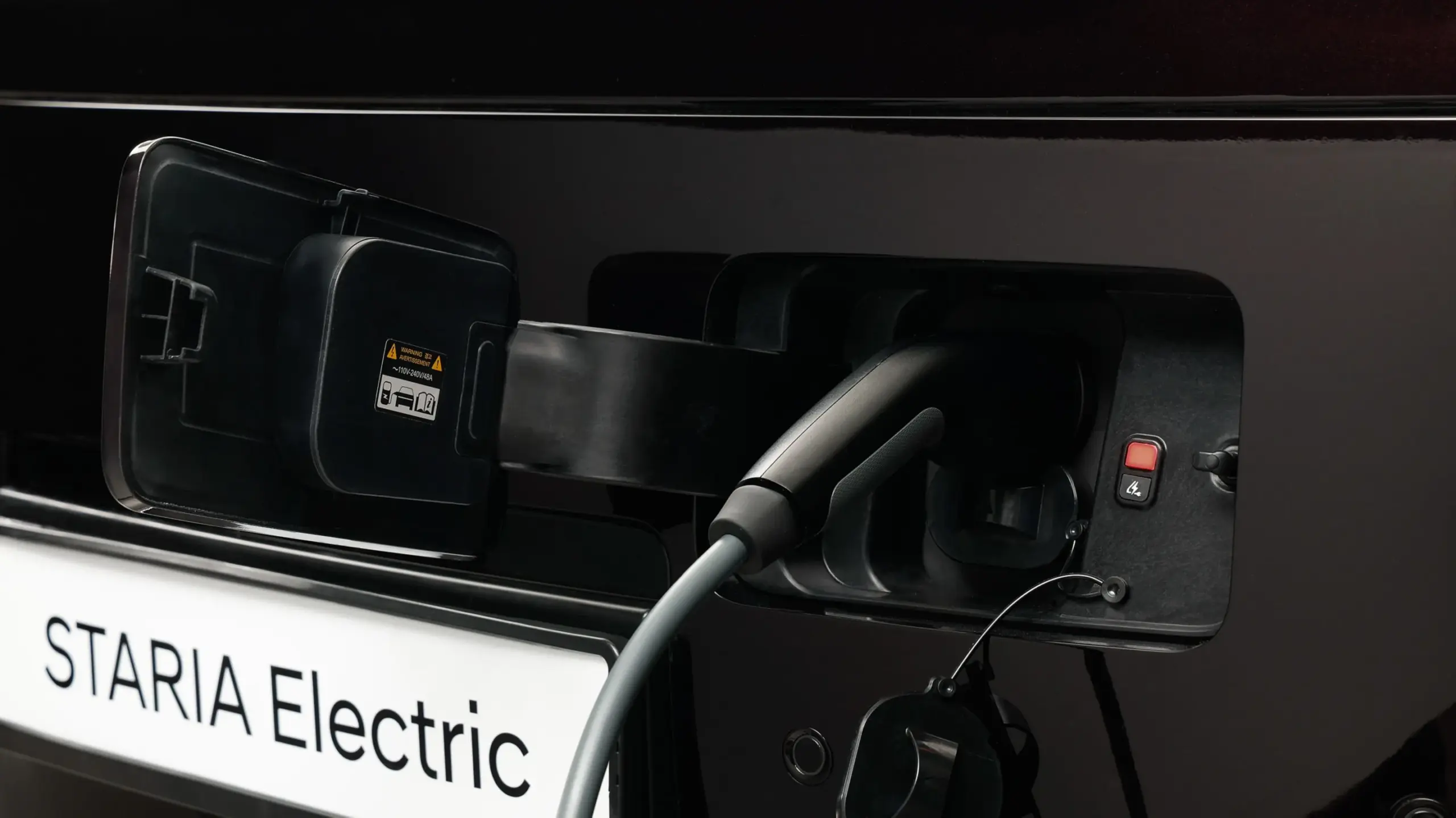 Hyundai STARIA Elektro wird an einer Ladestation geladen, Nahaufnahme des Ladeanschlusses.