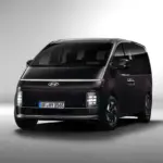 Hyundai STARIA Hybrid in dunkler Lackierung, aufgenommen aus leichtem Winkel von vorne vor neutralem Hintergrund.