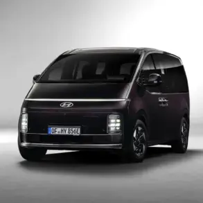 Hyundai STARIA Hybrid in dunkler Lackierung, aufgenommen aus leichtem Winkel von vorne vor neutralem Hintergrund.