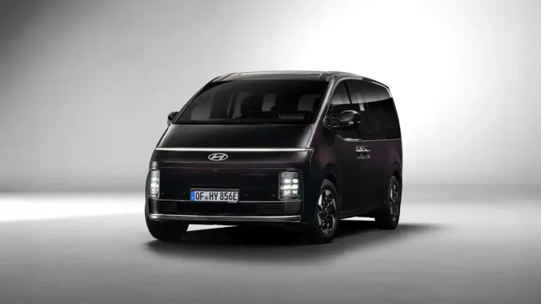 Hyundai STARIA Hybrid in dunkler Lackierung, aufgenommen aus leichtem Winkel von vorne vor neutralem Hintergrund.