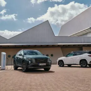 Zwei Hyundai Tucson, einer davon wird an einer Ladesäule geladen, vor zeitgenössischem Gebäude geparkt.