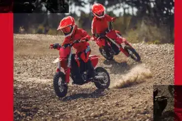 Zwei Kinder fahren die rote GASGAS MC-E 3 2024 auf einer Offroad-Strecke.
