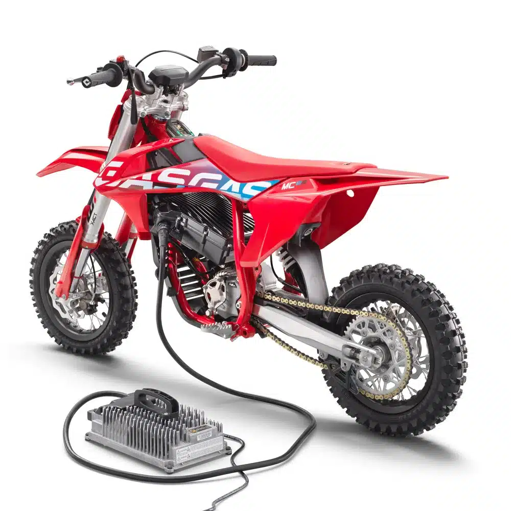 Rotes GASGAS MC-E 3 Elektro-Kinder-Motocross-Bike seitlich mit Ladegerät.