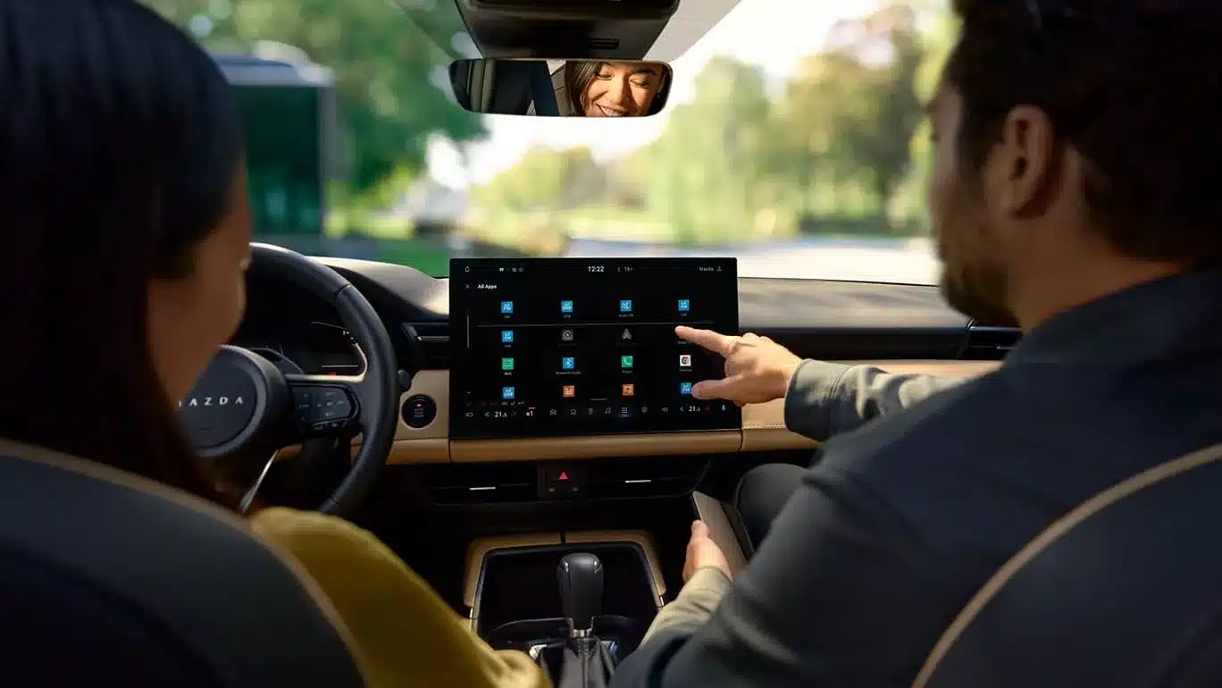 Fahrer und Beifahrerin nutzen das zentrale Touchdisplay im Innenraum des Mazda CX-5 der dritten Generation