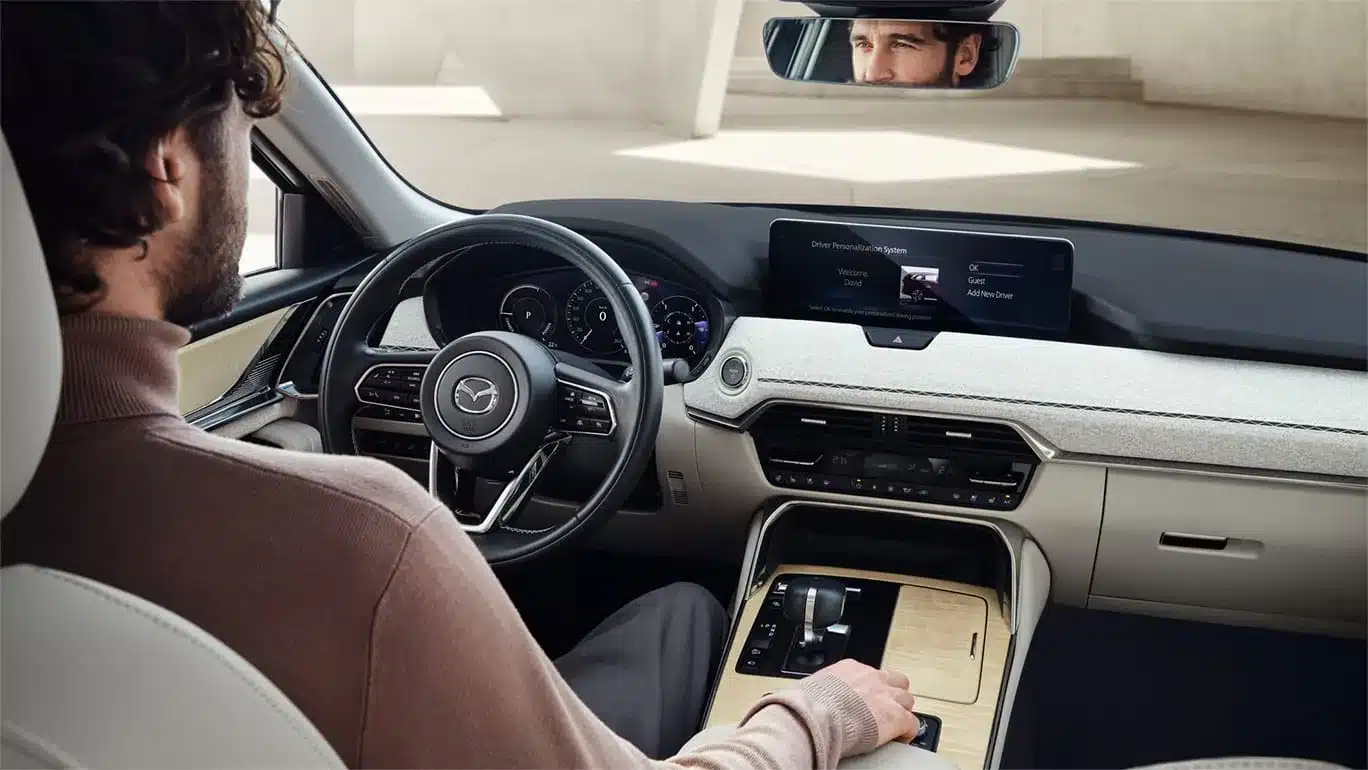 Blick auf das Cockpit, Lenkrad und Infotainment-Display des Mazda CX-60 2026 mit Fahrer