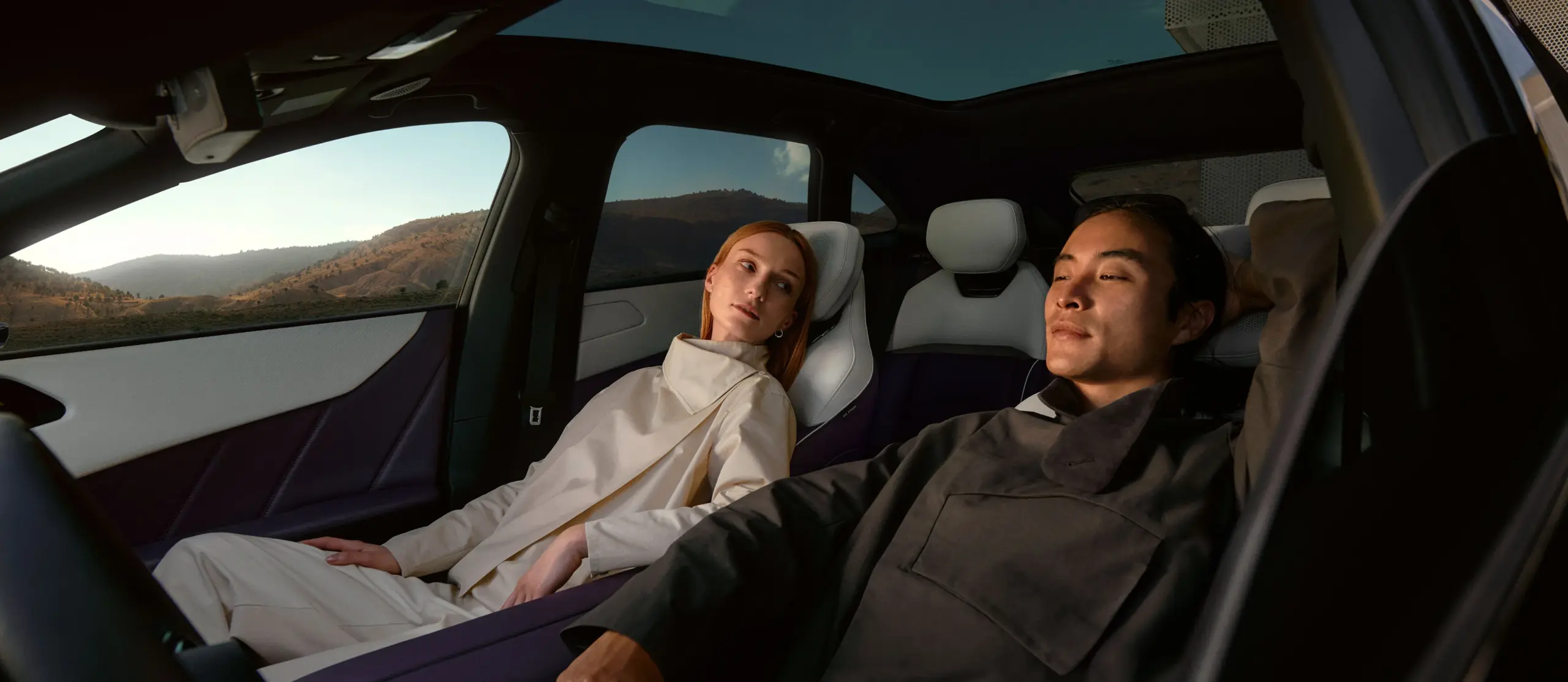 Innenaufnahme des Mazda CX-6e mit zwei entspannten Personen, elegantes und modernes Cockpit, Panoramaausblick auf die Landschaft