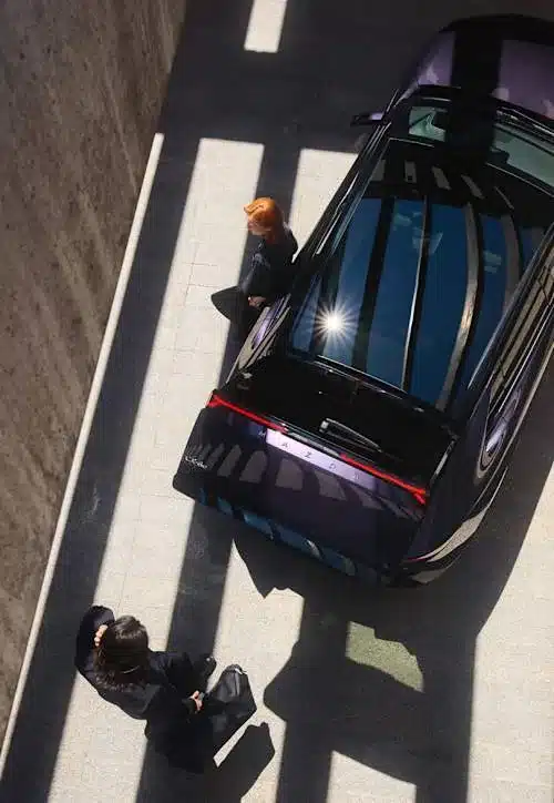 Mazda CX-6e von oben im Sonnenschatten, zwei Personen daneben