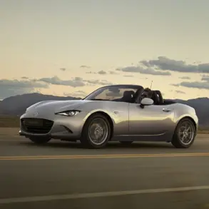 Mazda MX-5 2024 Roadster in Silber fährt bei Sonnenuntergang über eine Landstraße