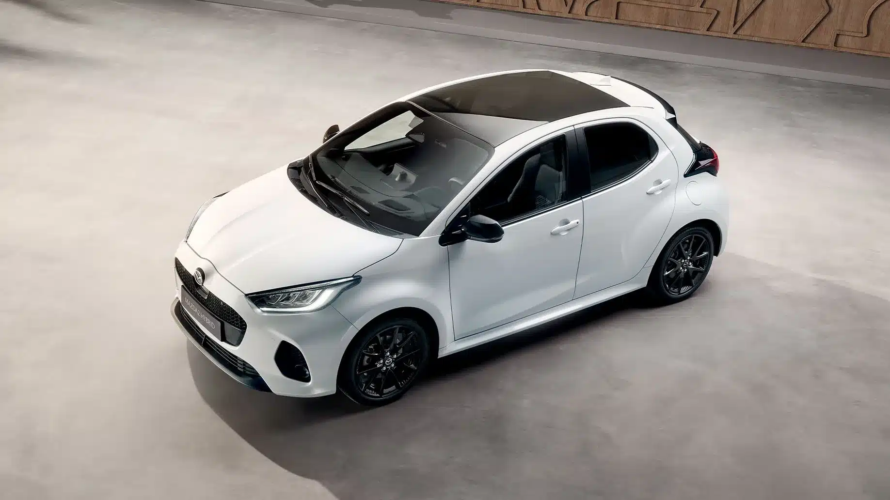 Mazda2 Hybrid 2024, weißes Kompaktfahrzeug mit sportlicher Linienführung, aufgenommen aus der Vogelperspektive.