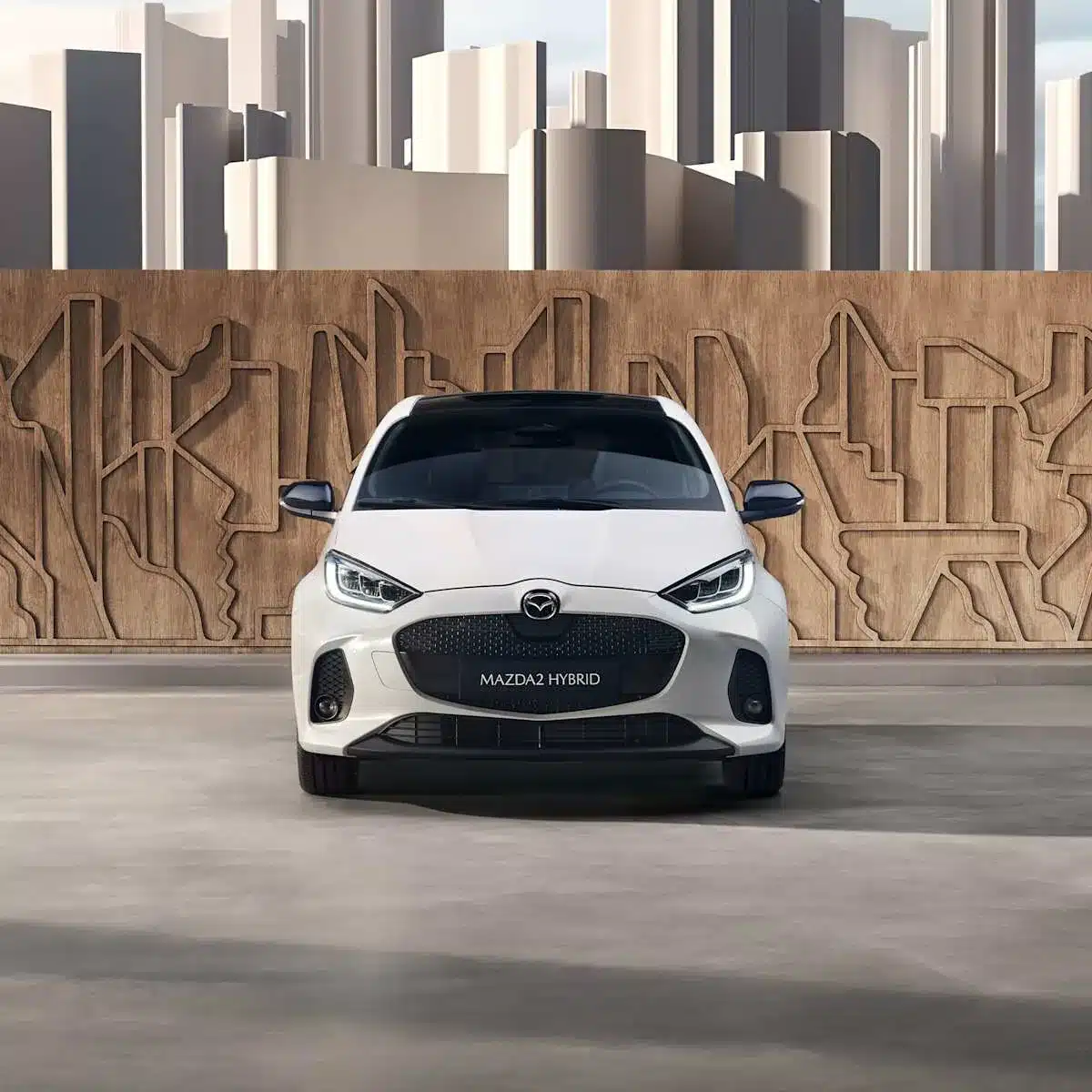 Mazda2 Hybrid 2024, weiß, frontal aufgenommen vor einer modernen Wand