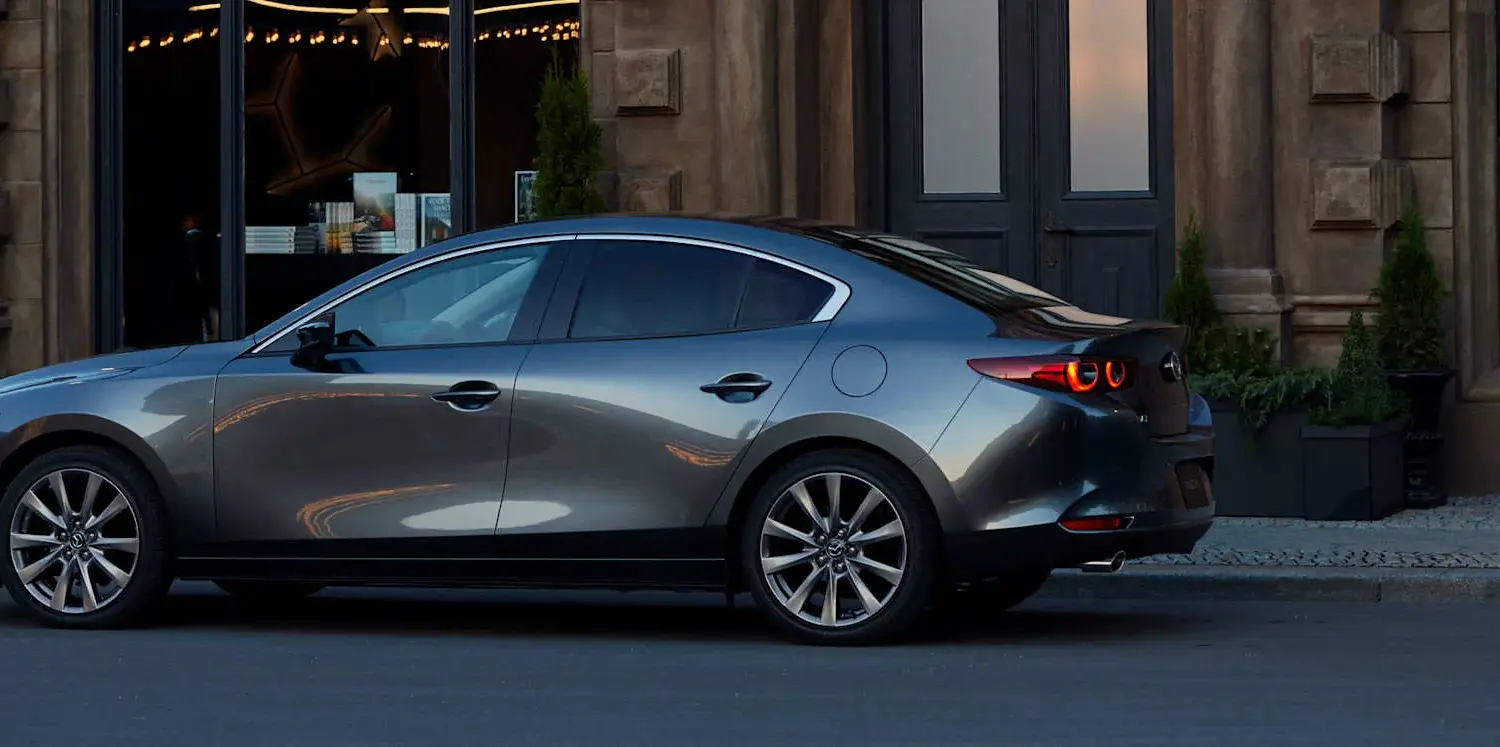 Mazda3 Fastback 2024 in Seitenansicht geparkt vor einem repräsentativen Gebäude
