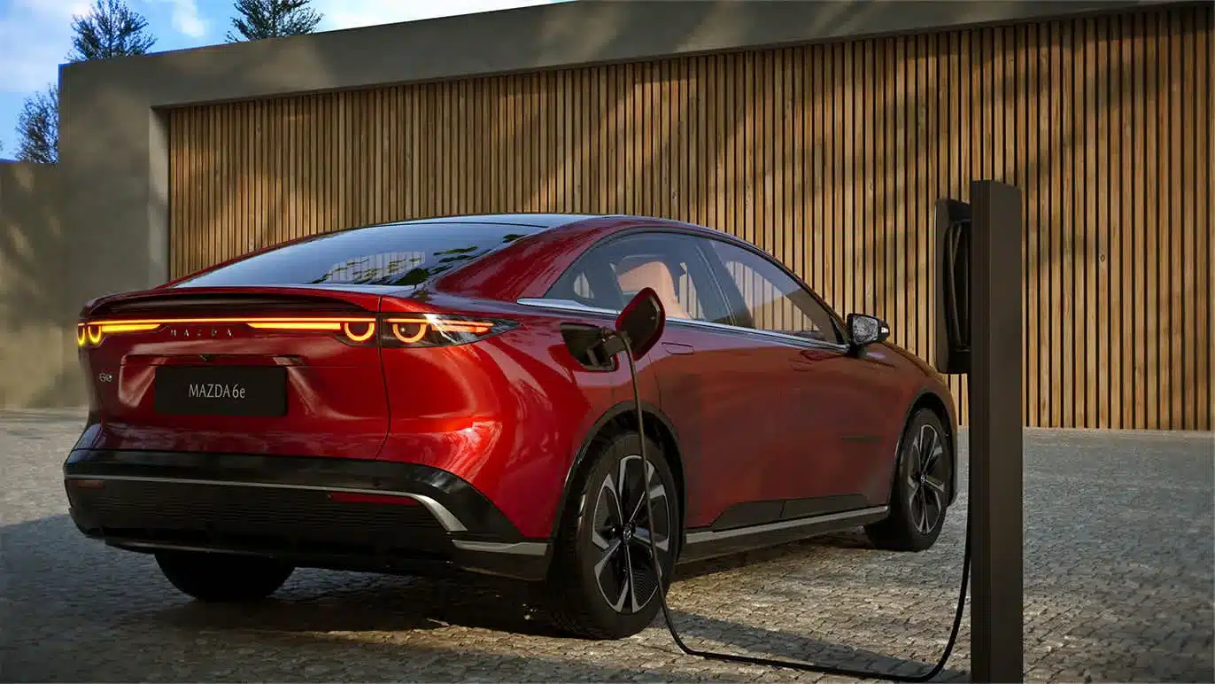 Roter Mazda6e an einer Ladestation, Fokus auf das elegante Heck mit leuchtenden LED-Rückleuchten.
