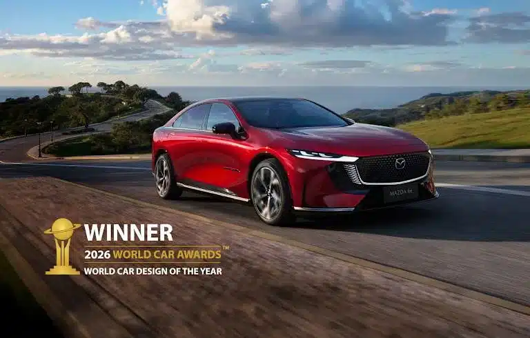 Roter Mazda6e fährt dynamisch auf einer Landstraße, gekrönt vom Titel World Car Design of the Year 2026.
