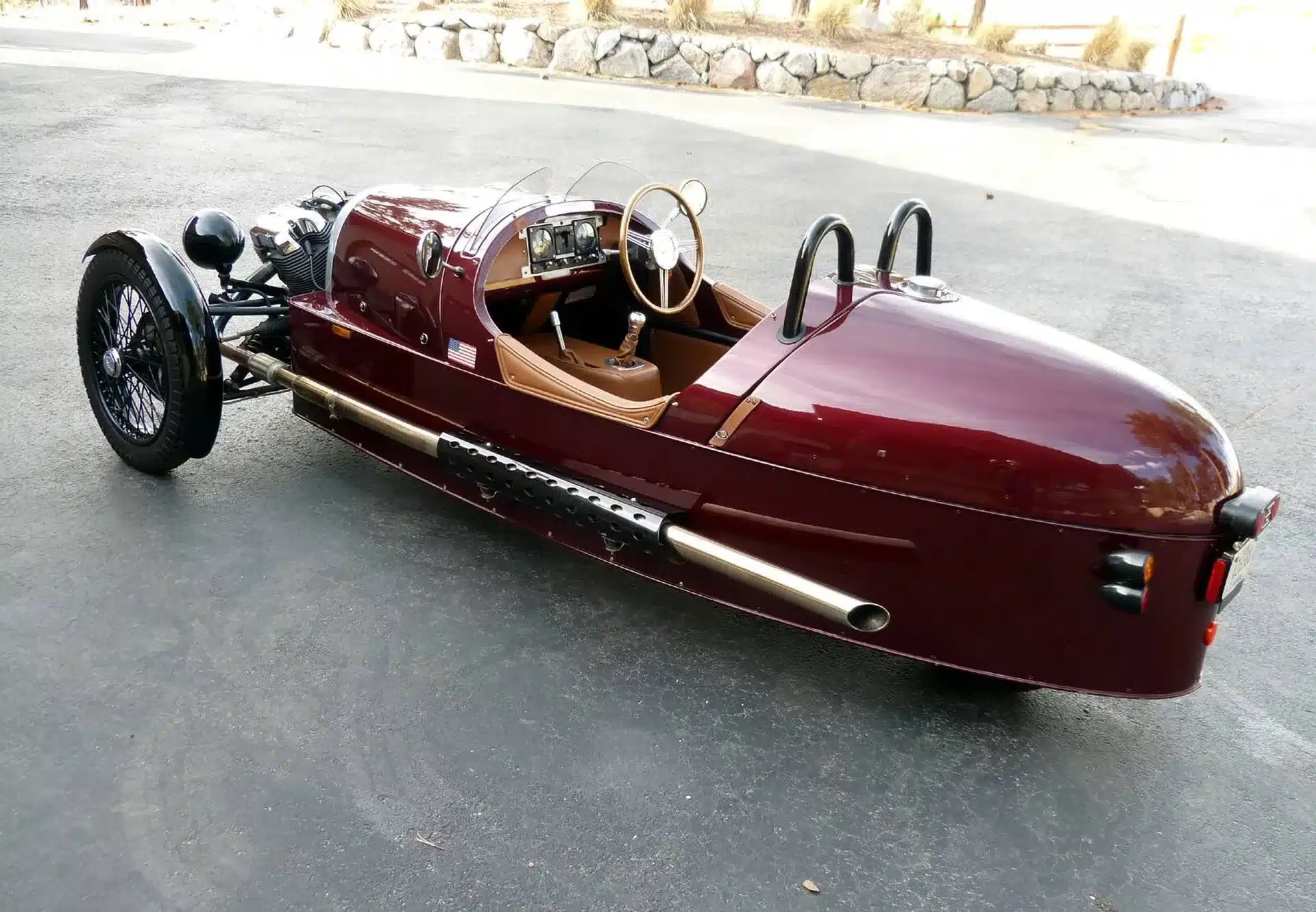 Morgan Three-Wheeler von 2012 in Bordeauxrot, offen mit zwei Sitzen und sichtbarem Auspuff, auf Asphalt stehend