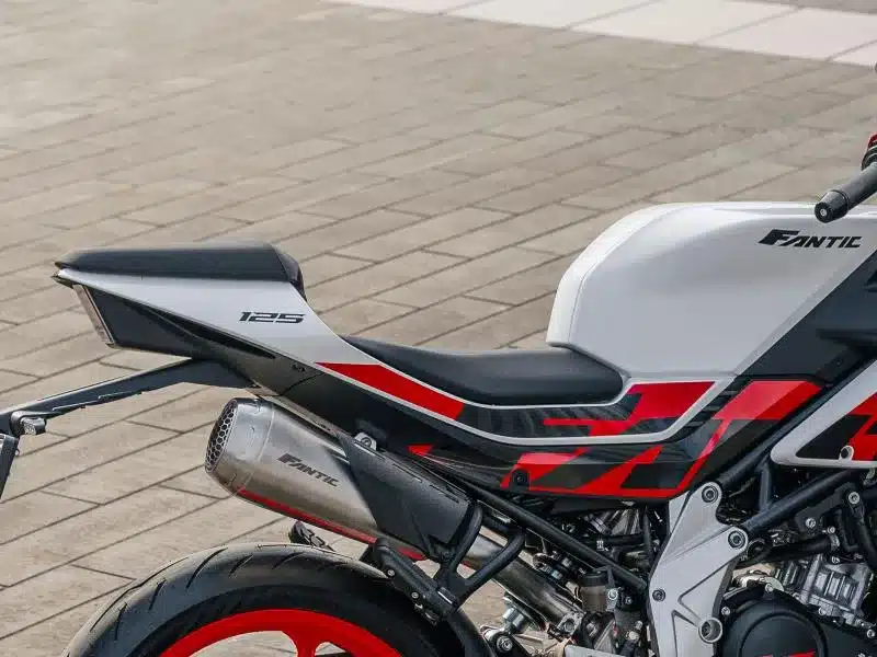 Detailaufnahme des hinteren Teils einer Fantic Stealth 125 Racing White mit Alu-Seitenplatten, Racing-Dekor, Schalldämpfer und Einzelsitz.