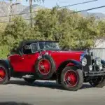 Stutz Model BB Custom Black Hawk Two-Passenger Speedster von 1928 in Rot und Schwarz auf einer Straße, Cabriolet-Verdeck und klassische Speichenräder.