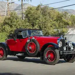Stutz Model BB Custom Black Hawk Two-Passenger Speedster von 1928 in Rot und Schwarz auf einer Straße, Cabriolet-Verdeck und klassische Speichenräder.